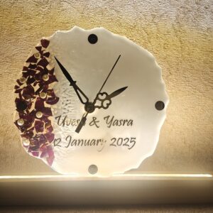 Handmade resin wall clock with personalized name 'Uvesh & Yasra' and date '12 January 2025', featuring floral embellishments and a wooden LED base.
