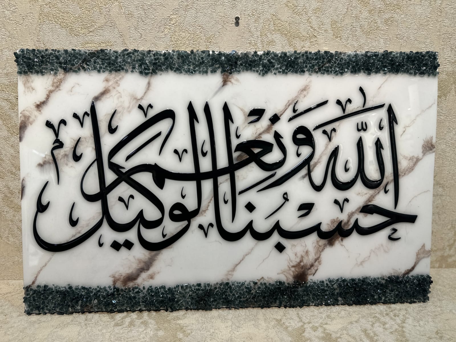 Luxury handcrafted Islamic wall art featuring "Hasbunallahu Wa Ni’mal Wakeel" in bold black Arabic calligraphy on a white marble-effect acrylic panel with crushed crystal edges.