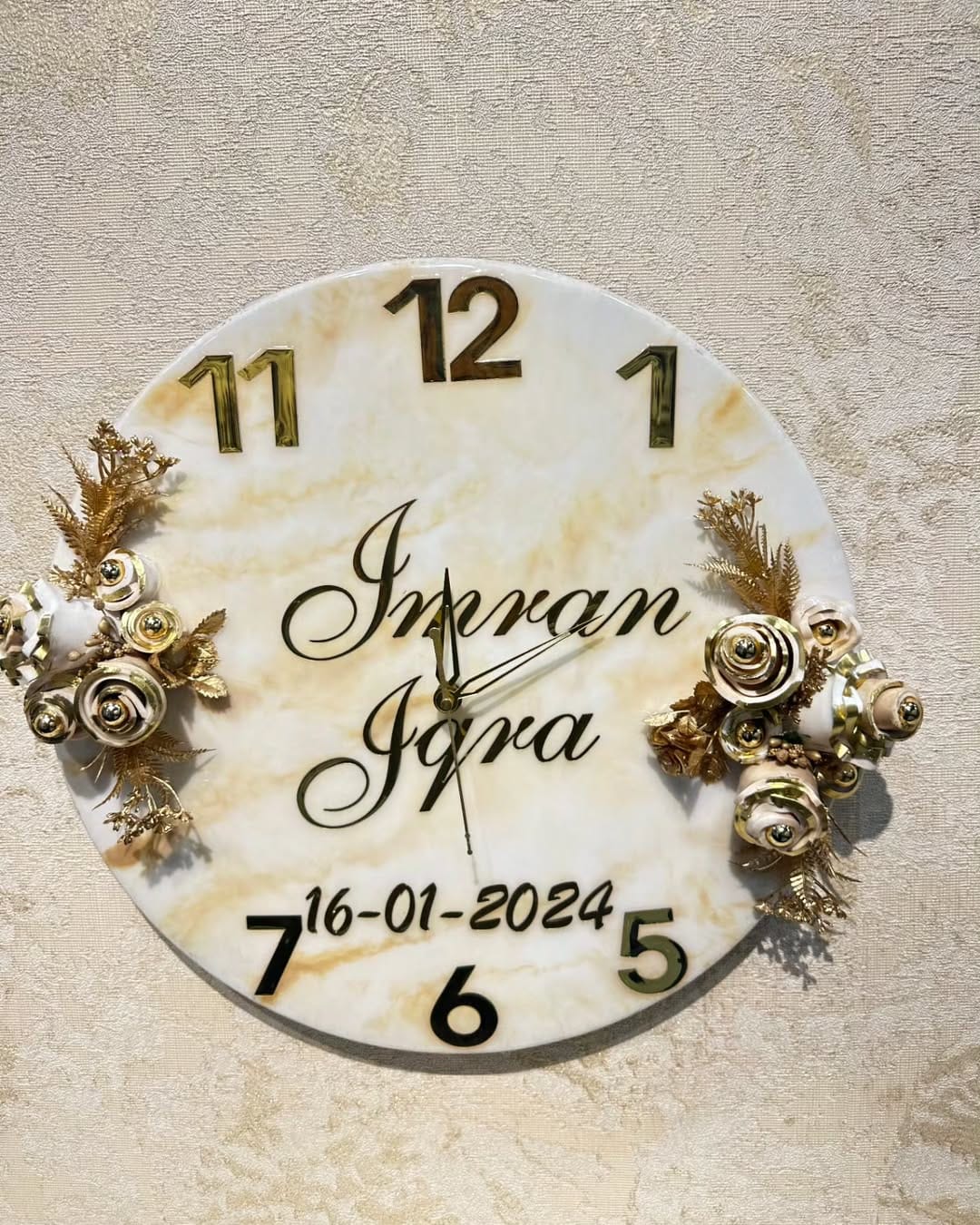 Personalized floral wall clock with custom names and date, featuring gold floral design and marble finish.