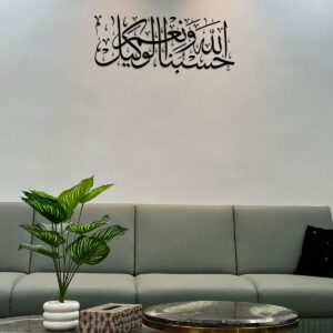 Modern Arabic calligraphy wall art in matte black acrylic displaying "Hasbunallahu Wa Ni’mal Wakeel" above a stylish sofa in a contemporary living room.
